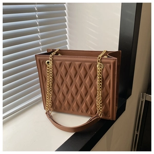Detail view of coffee brown quilted tote bag with gold metal chain straps and PU leather