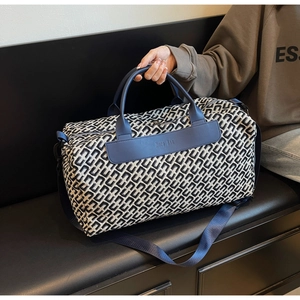 Dettaglio del tessuto jacquard geometrico con finiture in pelle blu su borsa da viaggio