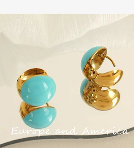 Close-up of French vintage gold-plated titanium earrings with turquoise enamel inserts