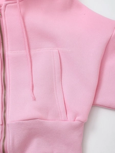 Close-up of pink zip-up hoodie featuring a metal zipper, side pockets and ribbed hemline