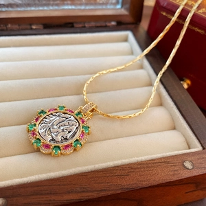 Detail view of a vintage gold-plated coin necklace with colorful zircon stones in a jewelry box