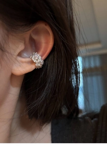 Close-up of a silver zircon flower ear cuff worn by a model in a natural setting