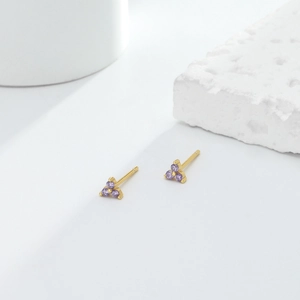 Macro view of gold plated triangle stud earrings with inlaid purple zircon stones