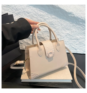 Detail showing crocodile-embossed leather trim and stitching on a beige square handbag