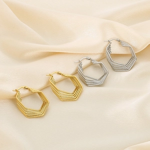 Detailed macro view of gold and silver multilayer hexagonal wire earrings on silk