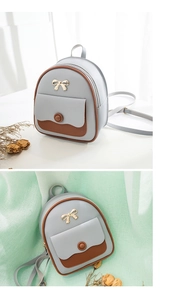 Close-up of mini grey-blue faux leather backpack with gold bow hardware and brown trim details