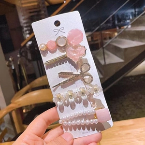 Detailed close-up of 5-piece rhinestone and pearl hair clip set on display card