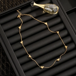 Minimalist gold necklace featuring eight heart pendants inlaid with zircon on a black tray