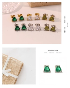 Macro shot of triangle cut emerald and clear gemstone stud earrings in gold three-claw setting