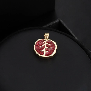 Vue macro du pendentif grenade plaqué or 18K avec textures rouges et détails de branches