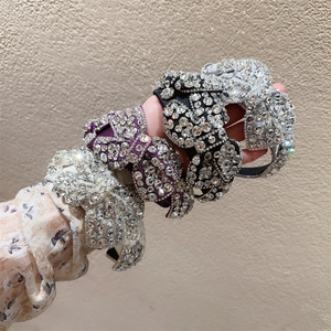 Nahaufnahme von vier Strass-Schleifen-Haarbändern in Silber, Lila und Schwarz in der Hand