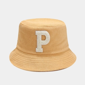 Détail d'un chapeau bob jaune en tissu éponge avec un écusson blanc en peluche lettre P