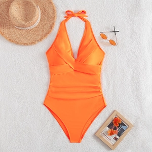 Detail of bright orange one-piece swimsuit with halter neck and ruched waist design