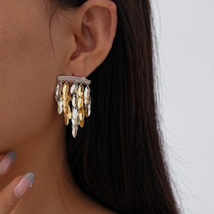 Close-up of bohemian metallic leaf tassel earrings with gold and silver tiered scales
