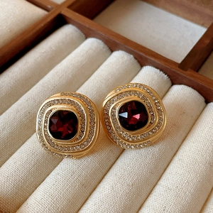 Detailed view of vintage gold swirl earrings with ruby red stone and crystal halo