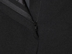 Close-up of metal zipper detail and fine fabric texture on black blazer and trousers set