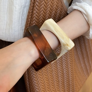 Detail of square resin bangles in amber and marble white on woman wrist