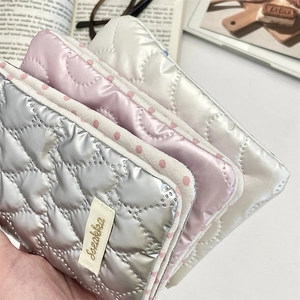 Detail of heart-quilted bow passport holder in silver pink and white shiny fabric