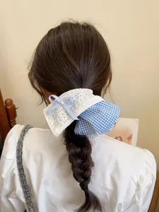 Detailed back view of a blue plaid and lace bow hair tie with pearl on a ponytail