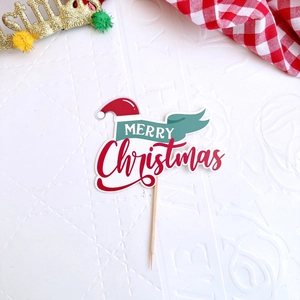 Detailed view of Merry Christmas cake topper with red hat and green banner on festive table