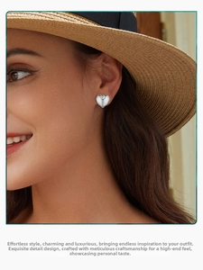 Close-up of minimalist S925 sterling silver heart earrings worn by a model in soft light
