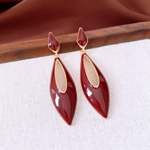 Détails macro des boucles d'oreilles émail bordeaux avec cadre évidé doré