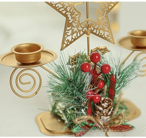 Close-up of golden metal double candle holder with festive pine needles and red berries