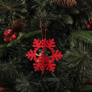 Détail d'un ornement de flocon de neige rouge en bois avec cloche sur un sapin de Noël