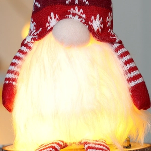 Close-up of glowing Christmas gnome with knitted snowflake hat and soft LED lighted beard