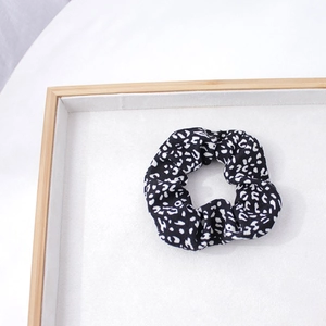 Détail du chouchou en tissu imprimé léopard noir et blanc sur un plateau en bois