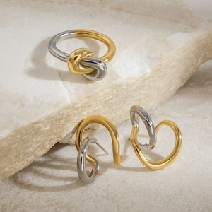 Minimalist 18K gold and silver two-tone knotted earring and ring set on stone base