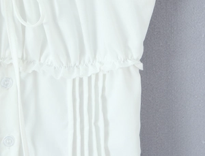 Close-up of white slim fit top featuring vertical ruffles and matching round buttons