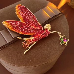 Close-up of vintage enamel fairy brooch with gradient wings and crystal star on velvet