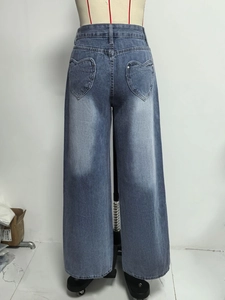 Detail of light blue washed denim jeans featuring unique heart-shaped back pocket design