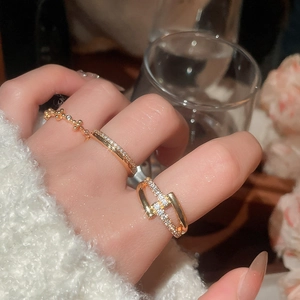 Close-up of three 18k gold plated zircon rings on a hand featuring a geometric cross design