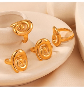 Detailed view of four golden spiral design rings on a ceramic display stand