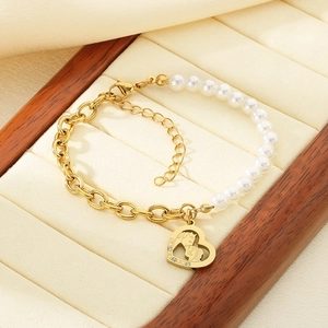 Detail of gold chain and pearl bracelet with heart pendant showing mother and child relief