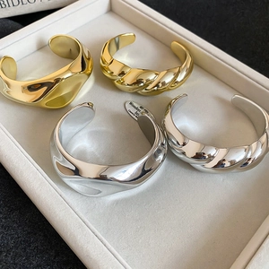 Close-up of chunky gold and silver twisted acrylic bangles on a display tray