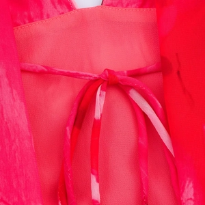 Detail eines Kleides mit rot-rosa Blumendruck und elegantem Bindeknoten am Rücken