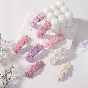Cute embroidered floral hair clips for girls in pink and white on a white marble background