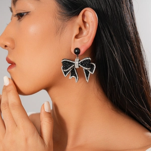 Macro detail of gothic black bow earrings featuring micro-pave dark rhinestones and silver trim