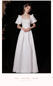 Detail of white satin wedding dress with puff sleeves, square neckline and pearl accents