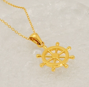 Detail view of a gold helm pendant necklace on a water ripple textured background