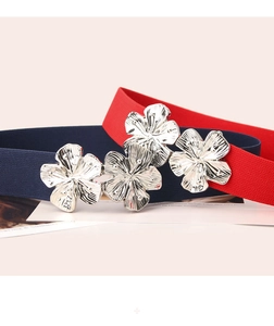 Close-up of elastic waist belts featuring silver floral metal buckles in blue and red