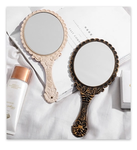 Detail of vintage hand mirrors featuring ornate floral relief and scrollwork handles