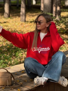 Red half-zip sweatshirt with California print shown on a model in an autumn outdoor setting