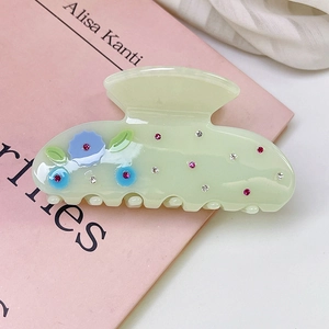 Close-up of light green acetic acid hair claw clip with blue flowers and pink rhinestones