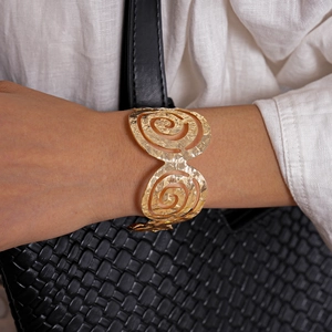 Gros plan sur un bracelet manchette doré en spirale avec texture martelée sur poignet