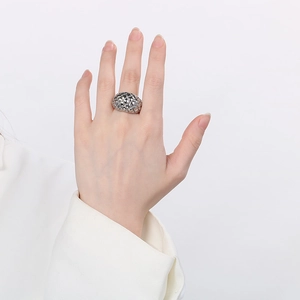 Detail of silver quilted pattern ring on index finger with a high-gloss metallic finish
