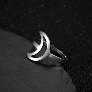 Minimalist silver moon cutout stainless steel open ring on dark textured rock